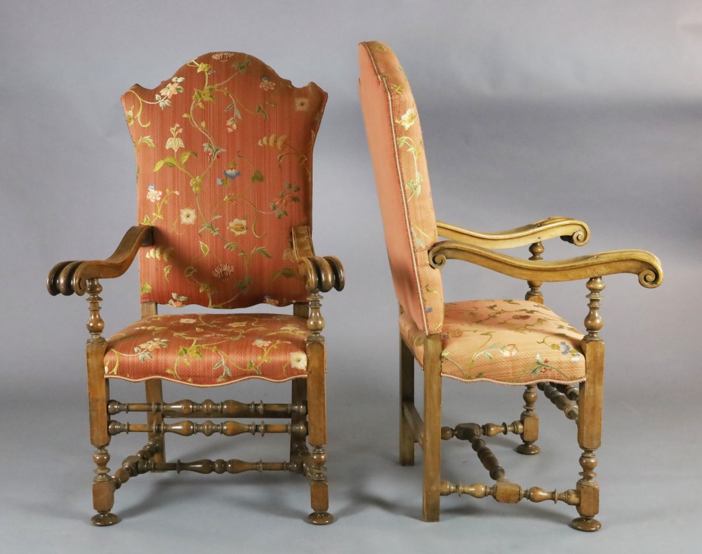 A pair of 19th century French 17th century style carved walnut high back armchairs, with floral upholstery, scroll arms and turned unde